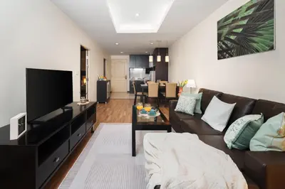 a living room with a couch and a flat screen tv at Verdant Vista King Suite near BTS with Modern Amenities in Khlong Toei