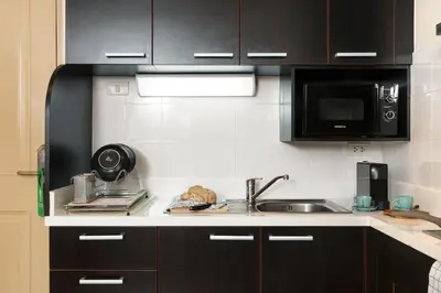 a kitchen with black cabinets and a sink and a microwave at Mystic Haven King Bed Suite with Balcony & City Views in Khlong Toei