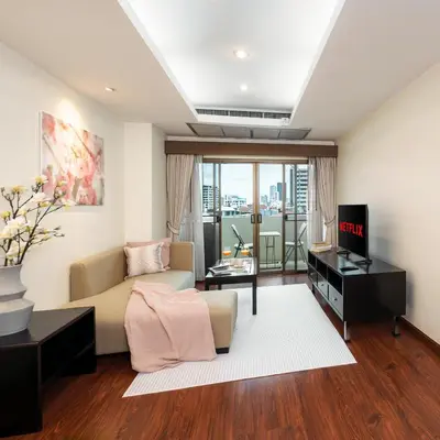 a living room with a couch and a television at Mystic Haven King Bed Suite with Balcony & City Views in Khlong Toei