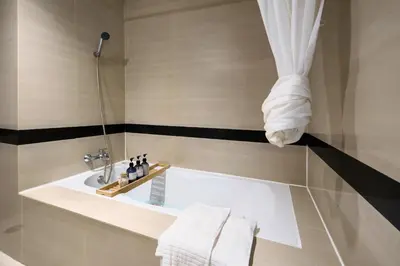 a bathroom with a tub and a shower with towels at Mystic Haven King Bed Suite with Balcony & City Views in Khlong Toei
