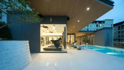 an external view of a house with a swimming pool at The Moment in Bangkok