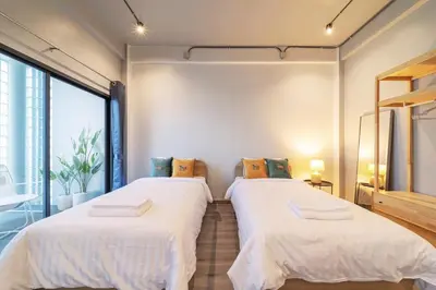 two beds in a room with a window at Bathtub, 2BR, 2BA, 120 Sqm, 6 Pax, Near BTS 7-11 in Bangkok