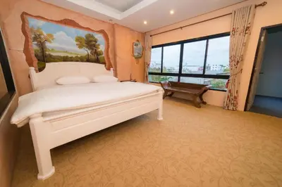 a bedroom with a large white bed and a window at Thongtara House Boutique Srinakarin in Bangkok