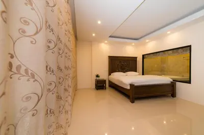 a bedroom with a bed and a curtain at Thongtara House Boutique Srinakarin in Bangkok
