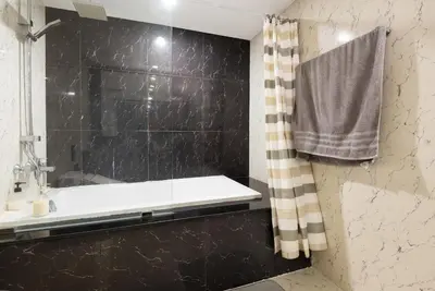 a bathroom with a black tiled shower with a tub at State tower City view Central River Station in Bangkok