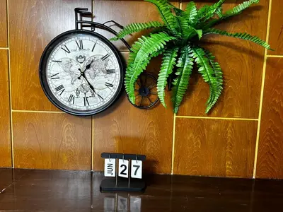 a clock hanging on a wall next to a plant at Nich Houses Craft&More in Sathani Sala Ya
