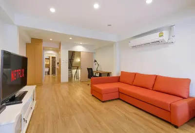 a living room with a orange couch and a flat screen tv at Bangkok Japanese designed 3BR Home Ekkamai BTS in Bangkok