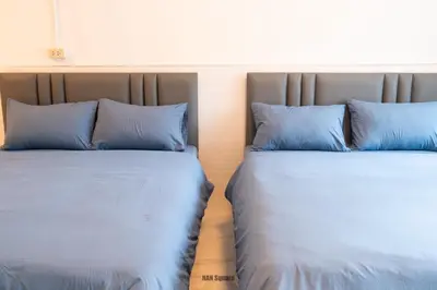 two beds with blue pillows sitting next to each other at Nan Square II in Bangkok