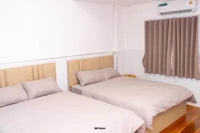 two beds in a small room with a window at Nan Square II in Bangkok