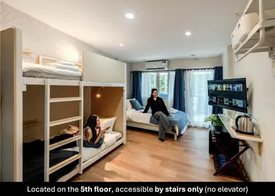 two women sitting on a bed in a room with bunk beds at Blue House 191 Hometel in Chinatown