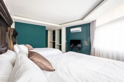 a bedroom with two white beds and a blue wall at Lemoncurd Bread and Coffee in Bangkok