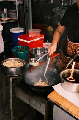 a person is cooking food on a grill at 2 BR Sleeps6 I City Center Silom in Bangkok