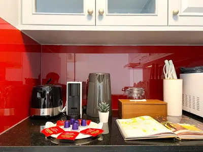 a kitchen with red walls and a counter with a coffee maker at Stylish 2BR City View - BTS St.Louis - Ultra Fast Wifi in Bangkok