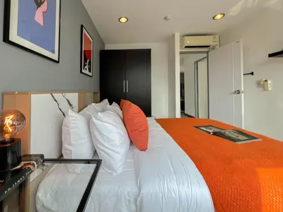 a bedroom with a large white bed with orange pillows at Stylish 2BR City View - BTS St.Louis - Ultra Fast Wifi in Bangkok