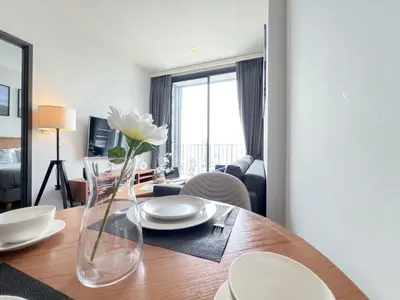 a dining room table with a vase with a flower in it at Urban Chic Living - 1BR - Ultra Fast WiFi - BTS Asoke in Bangkok
