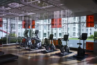 a gym with cardio equipment in front of a large window at คอนโดศุภาลัยเวลลิงตัน2 in Bangkok