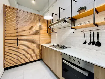 a kitchen with wooden cabinets and a stove top oven at Vélin - Samsen in Bangkok