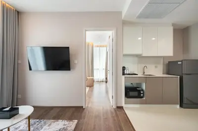 a kitchen and living room with a television on a wall at The Rich Grand Residence Sukhumvit in Bangkok