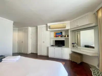 a white bedroom with a bed and a mirror at Trinity City View 3BR Spacious Family Silom in Bangkok