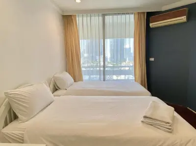 two beds in a hotel room with a window at Trinity City View 3BR Spacious Family Silom in Bangkok