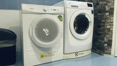 a washing machine sitting next to a brick wall at Trinity City View 3BR Spacious Family Silom in Bangkok