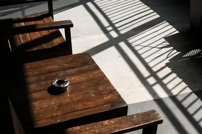 a wooden bench sitting in the shadows of a building at THA City Loft by TH District in Bangkok