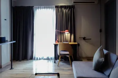 a living room with a table and a desk with a lamp at THA City Loft by TH District in Bangkok