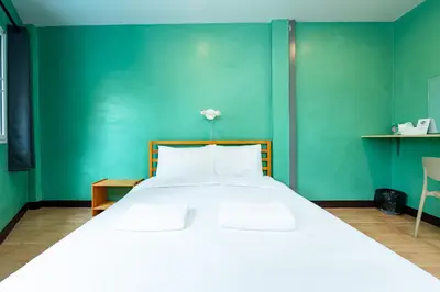 a bedroom with a large white bed with a green wall at xxGO INN The Giant Swing - เสาชิงช้า in Bangkok