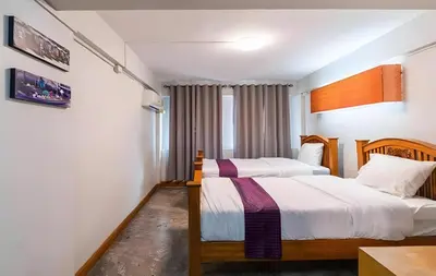 a bedroom with two beds and a table at XX GO INN Khaosan - โกอินน์ ถนนข้าวสาร in Bang Bua Thong Railway Station