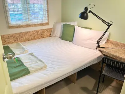 a bed in a room with a desk and a lamp at 326 Podtel at The Breakie Bar in Bangkok