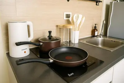a kitchen counter with a frying pan on a stove at Central next to Shopping 1 Bedroom Condo - 2 Min to BTS Asok and Terminal 21 in Bangkok
