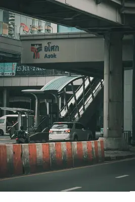 a car driving under a bridge with a train at Central next to Shopping 1 Bedroom Condo - 2 Min to BTS Asok and Terminal 21 in Bangkok