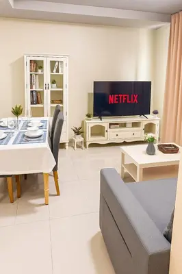 a living room with a table and a tv on a wall at Central next to Shopping 1 Bedroom Condo - 2 Min to BTS Asok and Terminal 21 in Bangkok