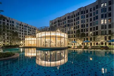 a building with a large pool in front of a building at Resort style family room near BTS Bearing in Ban Khlong Samrong