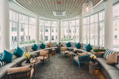 a large room with couches and chairs and windows at Resort style family room near BTS Bearing in Ban Khlong Samrong