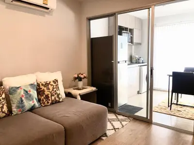 a living room with a couch and a sliding glass door at Resort Style room Ellio Monthly Available in Bangkok