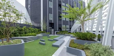 a courtyard with trees and benches in front of a building at The Rich Rama 9 Luxury Condos in Sathani Ban Hua Mak