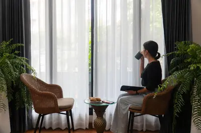 a woman sitting on a chair drinking from a cup at Poshtel 56 in Bangkok