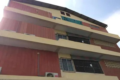 a tall red building with many windows at Sukhum Sukhumvit-Onnut Guest House in Amphoe Phra Khanong