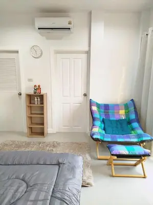 a room with a bed and a chair and a clock at Hidden Gems Residence in Ban Sala Daeng