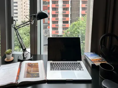 a laptop computer sitting on a desk with a book at Saladaeng Residences at Silom in Bangkok