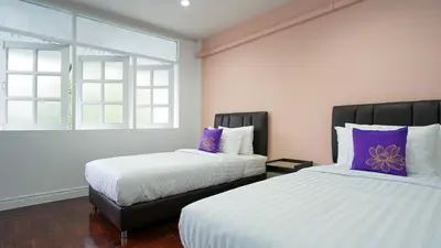 a bedroom with two beds with purple and white pillows at BTS Asoke 6bedroom townhouse in Bang Kapi