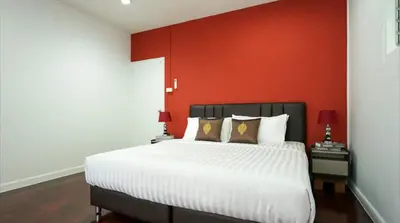 a bedroom with a large bed with a red wall at BTS Asoke 6bedroom townhouse in Bang Kapi
