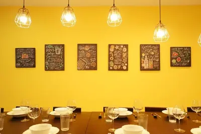 a dining room with a table with glasses and a yellow wall at BTS Asoke 6bedroom townhouse in Bang Kapi