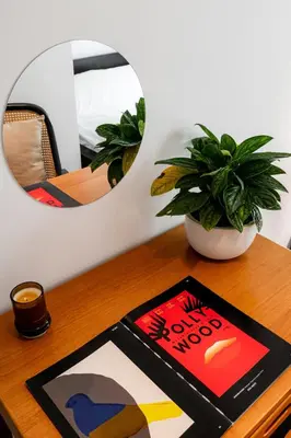 a book on a table with a plant and a mirror at Nap Boriphat in Bangkok