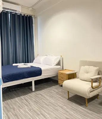 a bedroom with a bed and a chair and a window at Moon Pīti in Bangkok