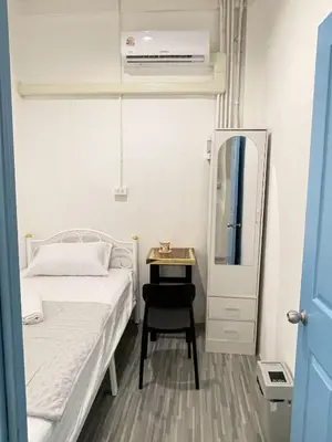 a small bedroom with a bed and a table at Moon Pīti in Bangkok