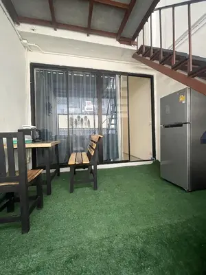 a living room with a table and chairs and a kitchen at Moon Pīti in Bangkok