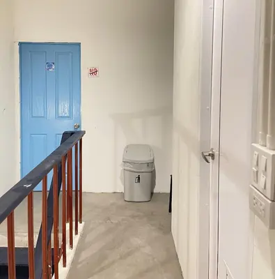 a hallway with a blue door and a trash can at Moon Pīti in Bangkok