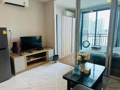 a living room with a television and a table with flowers at Artisan Ratchada Prime Studio Condos in Bangkok